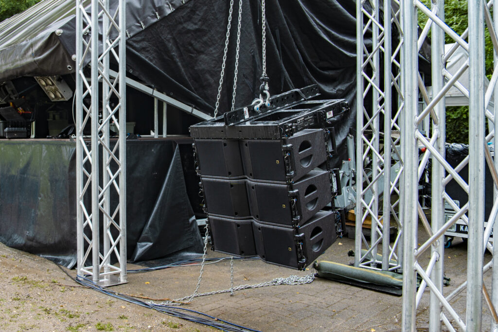 L'Acoustic Kara Line Array Lautsprecher an einem Kettenzug hängend, mit einer Bühne und Traversen im Hintergrund